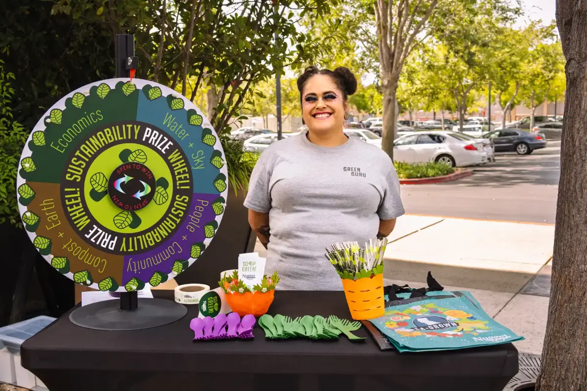 Nugget Markets Sustainability Coordinator at kiosk with prize wheel
